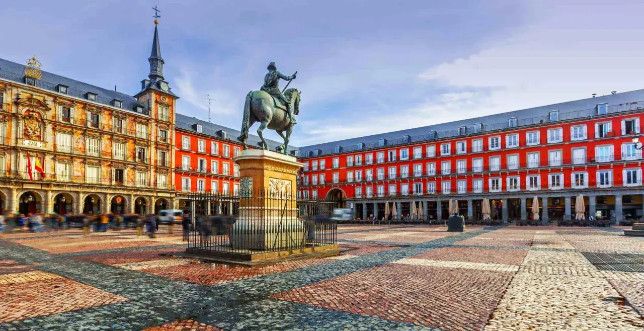 Plaza Mayor de Madrid, con estatua ecuestre y edificios rojos. Imagina llegar en tren santiago madrid y ver esta maravilla.