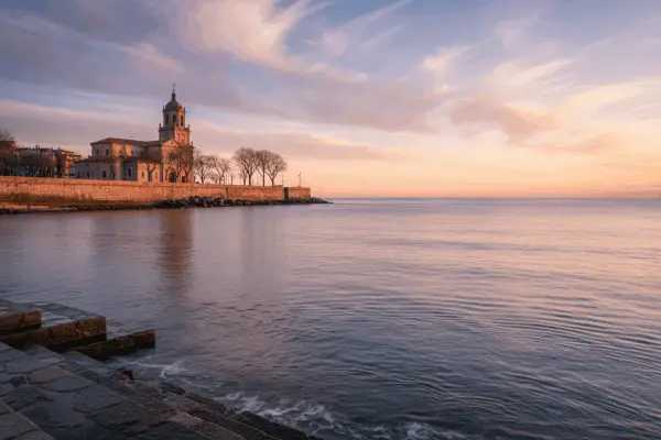Edificio histórico junto al mar al amanecer, evocando poemas del mar.